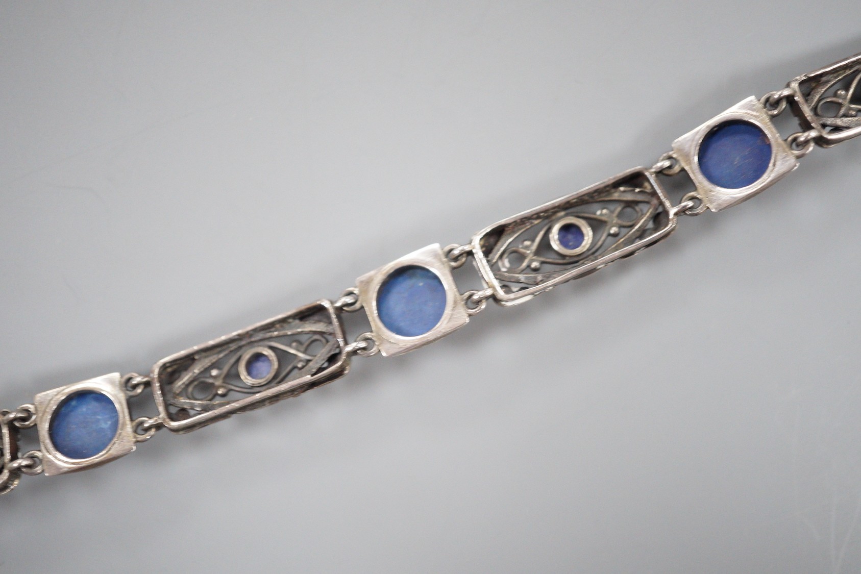 A stylish early 20th century white metal and two colour ten stone lapis lazuli?? or possibly enamel?? cabochon set bracelet, stamped 'Liberty Sterling', 18.3cm.